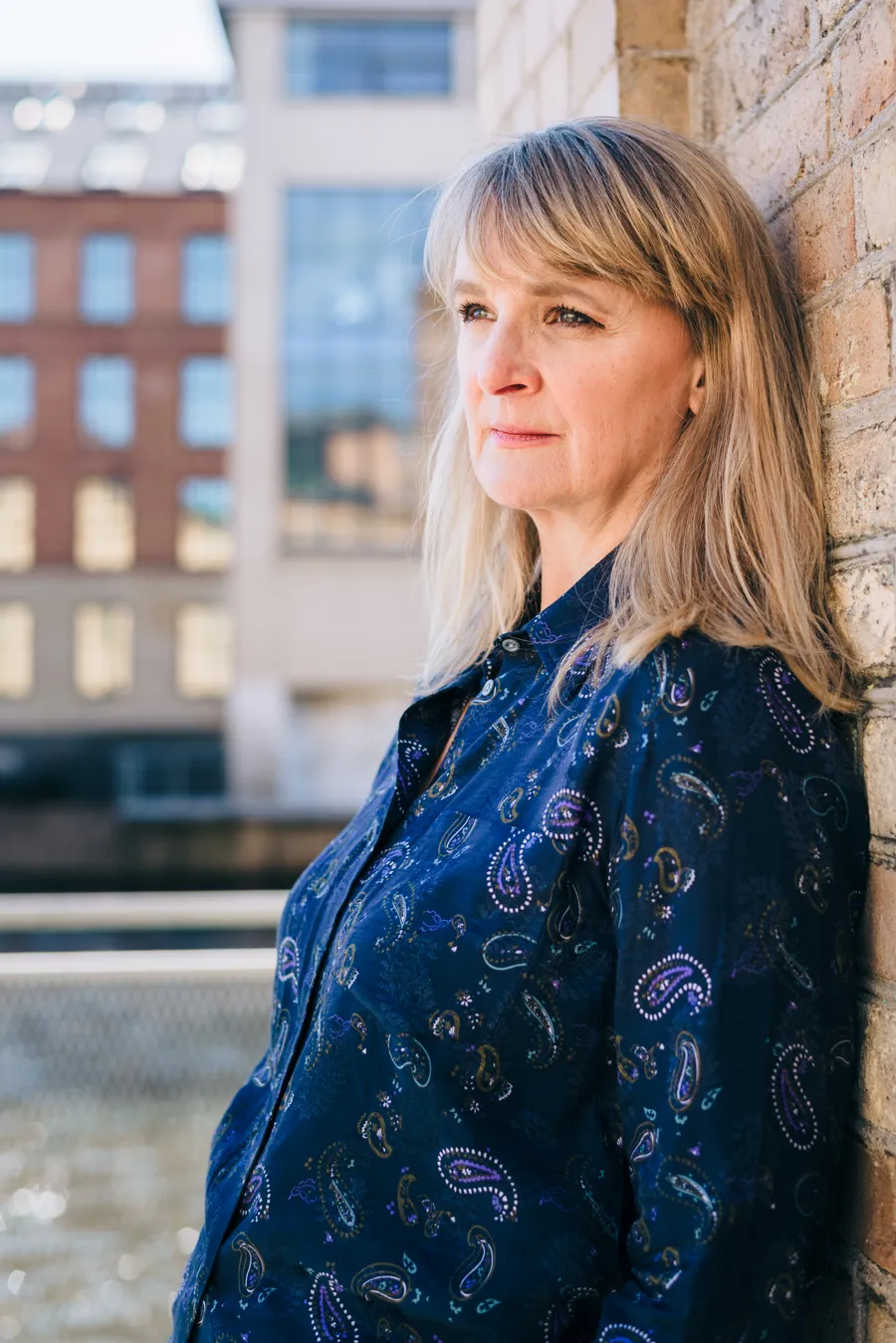 A woman leaning up against a brick wall.