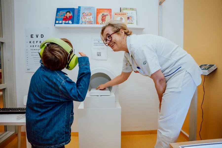 Ett barn med hörlurar och en kvinnlig läkare.