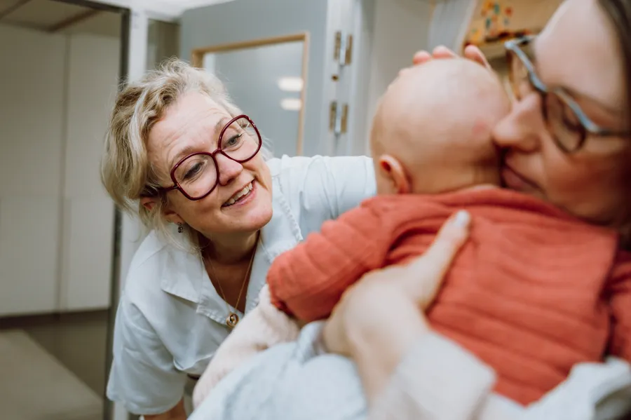 En kvinnlig läkare ler mot en bebis.