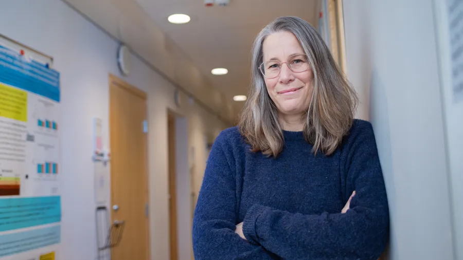 A woman standing next to a wall with a poster on it.
