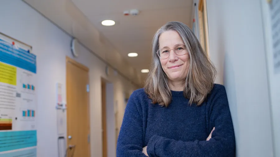 En kvinna som står bredvid en vägg med en affisch på.