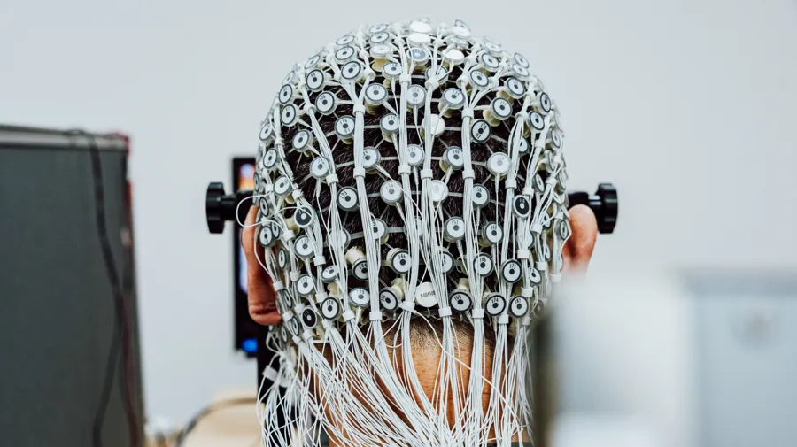 En man med sladdar på huvudet som arbetar med en dator.