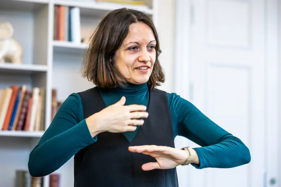 En kvinna står framför en bokhylla.