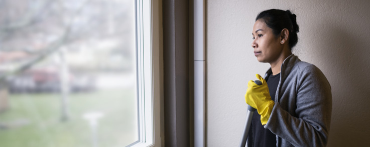 Kvinnlig lokalvårdare som tittar ut genom ett fönster. 