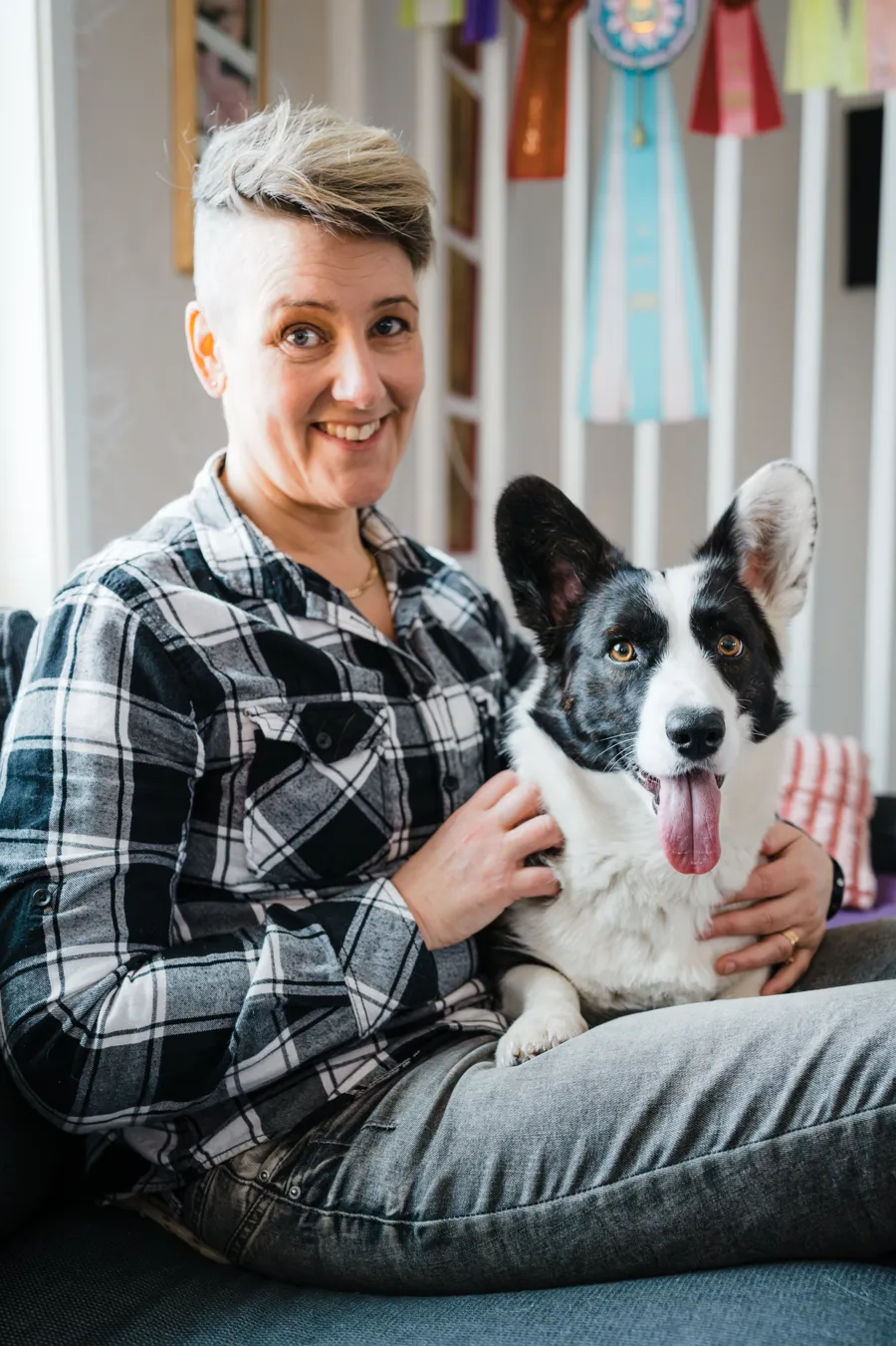 A woman sitting on a couch holding a dog.