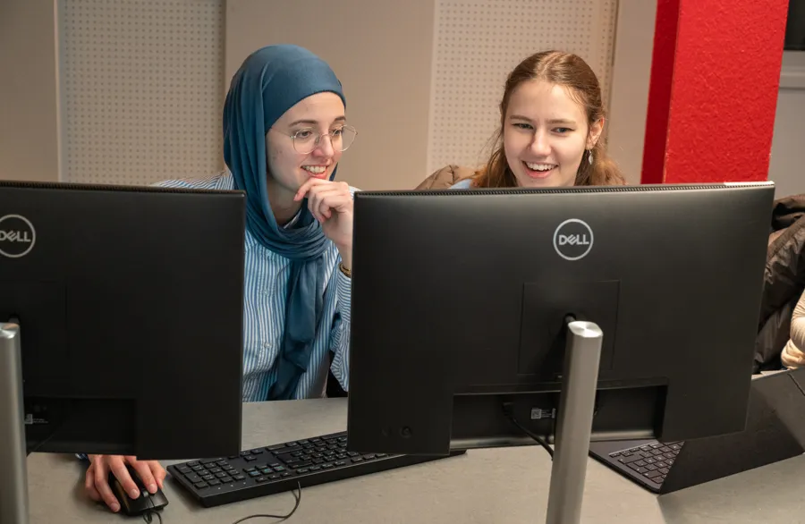 Två kvinnor sitter framför två datorskärmar.