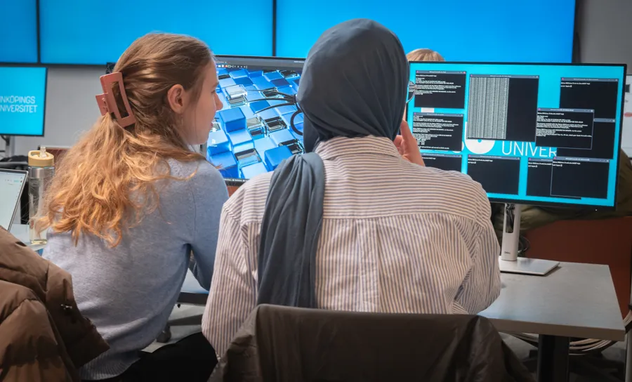 Två personer som sitter framför en datorskärm.