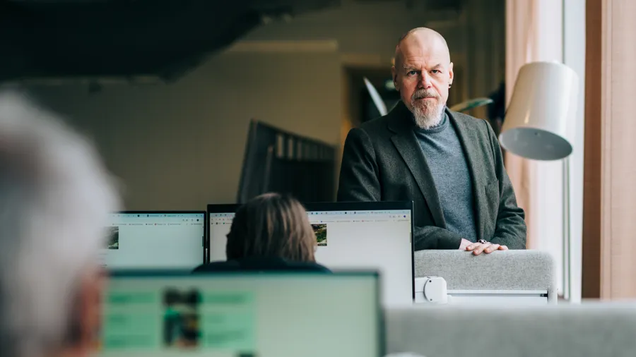 En man står framför två datorskärmar.