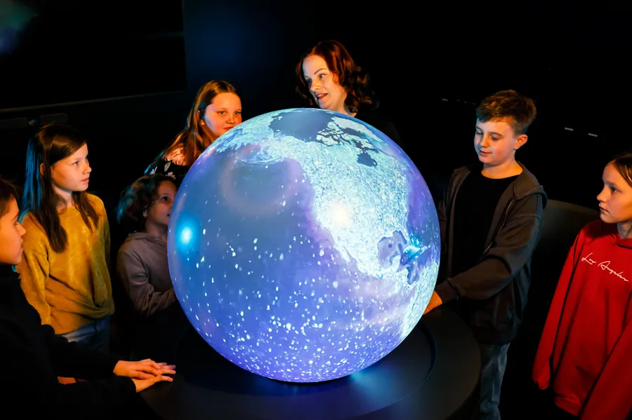 A group of people standing around a large globe.