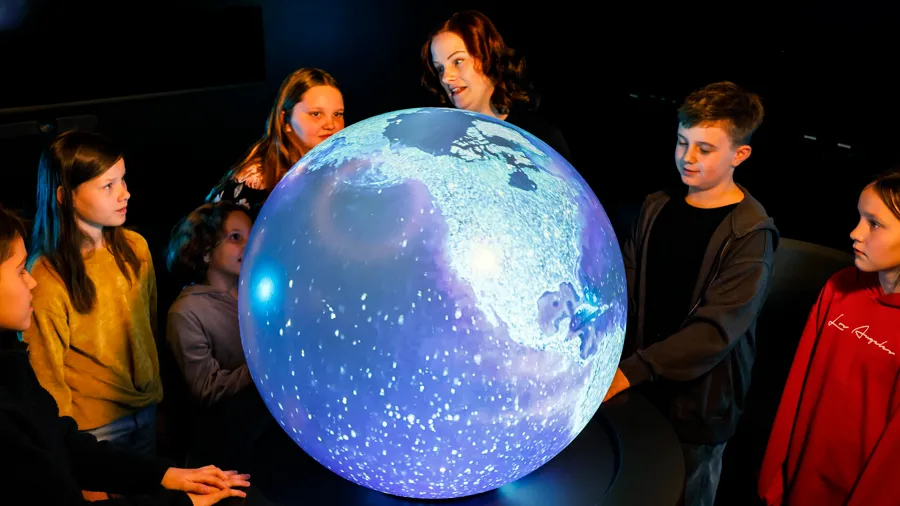 En grupp människor som står runt en stor jordglob.