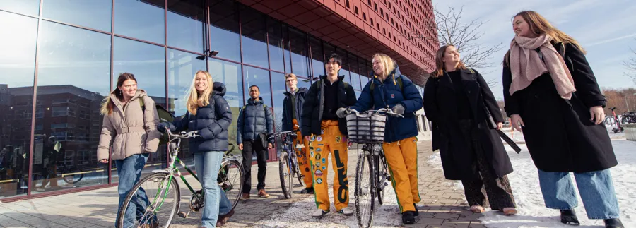 En grupp människor som går tillsammans utanför en byggnad med ett stort glasparti nedtill.