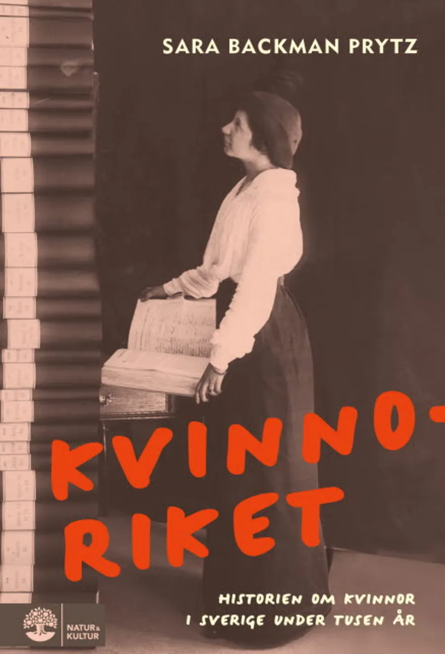 En kvinna som står bredvid en trave böcker.