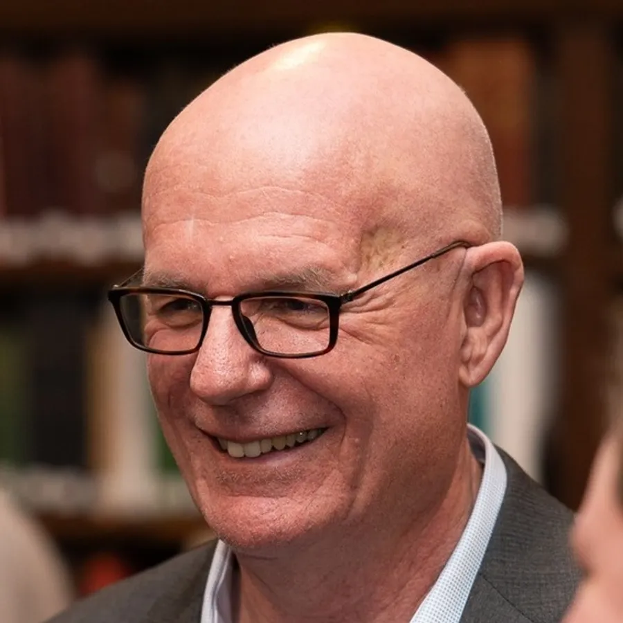 En man med glasögon som ler mot kameran.