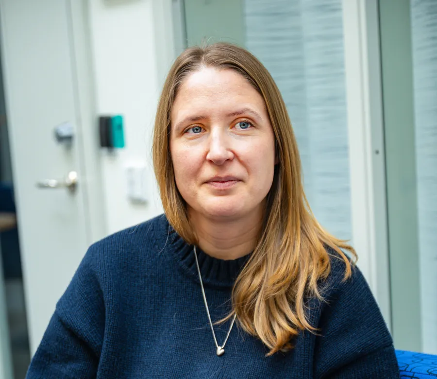 En kvinna i blå tröja sitter på en blå soffa.