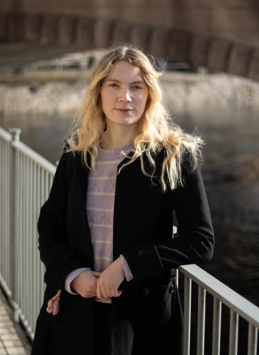 En kvinna står på en bro intill ett vattendrag.