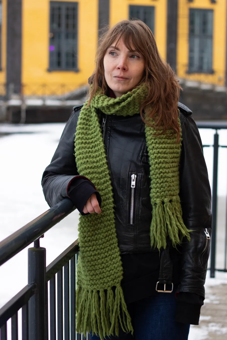 En kvinna med en grön halsduk och en svart jacka.