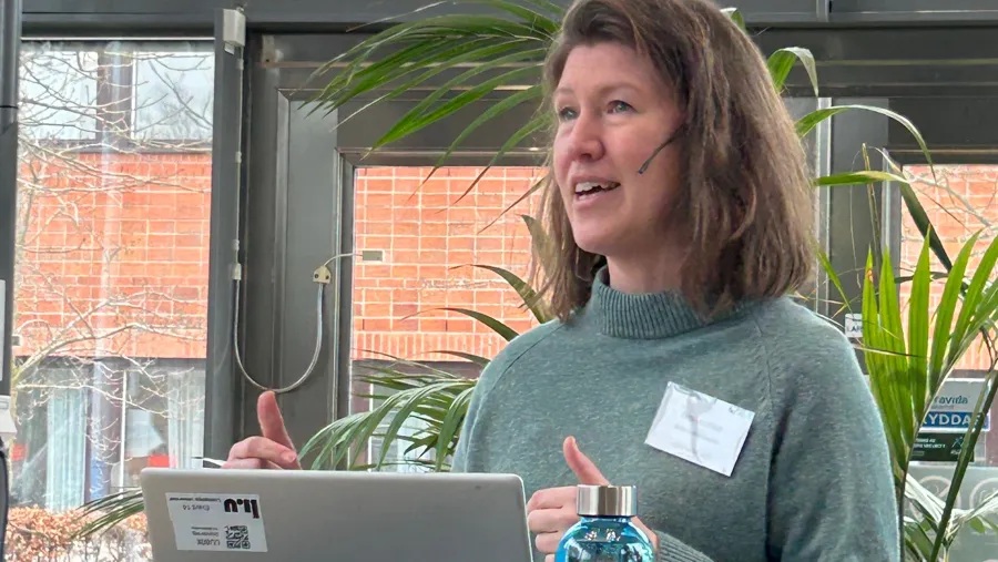 En kvinna står framför en bärbar dator.