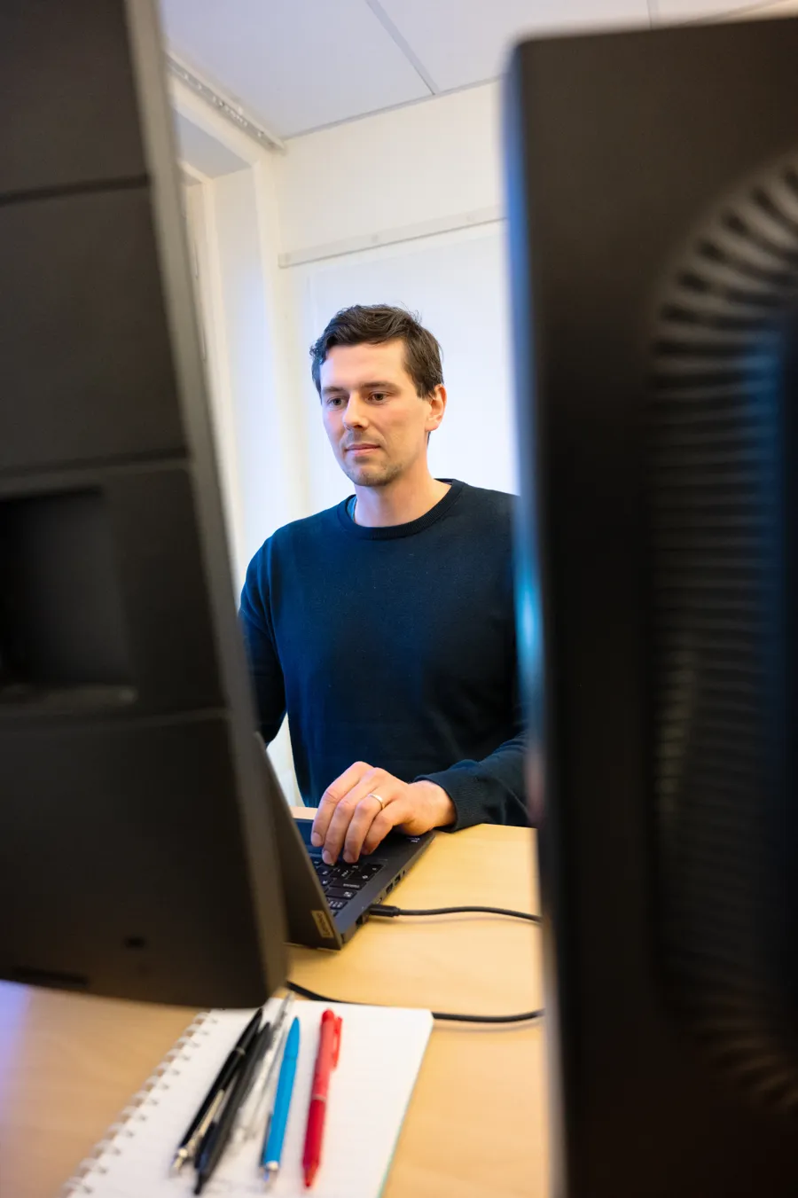 En man sitter vid ett skrivbord och använder en dator.