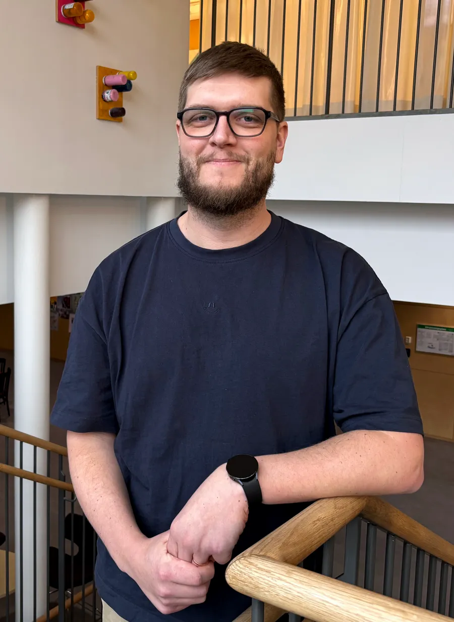 En man kollar in i kameran i en trappa.