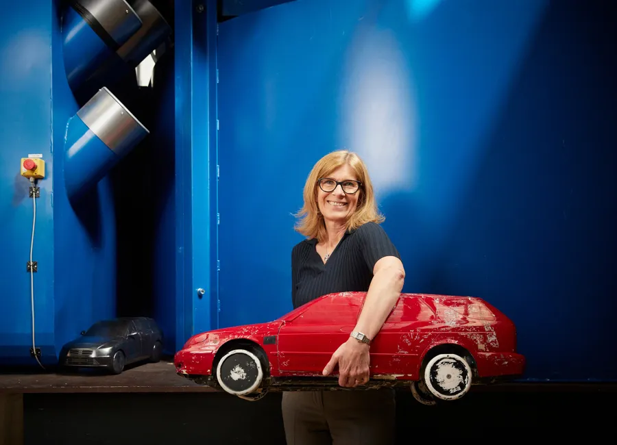 En kvinna som står bredvid en röd leksaksbil.