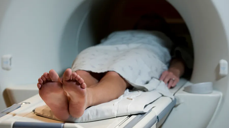 En person som ligger i en magnetröntgen med fötterna uppe.