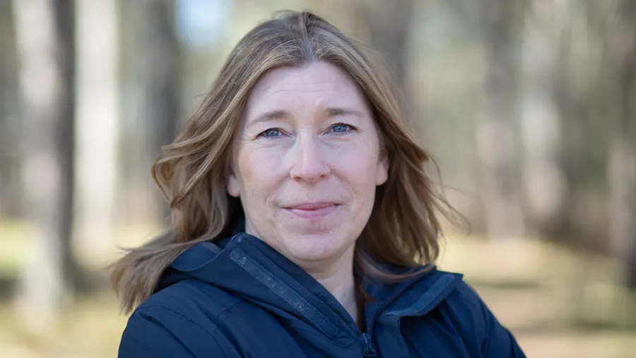 En kvinna som står i en skog med träd i bakgrunden.