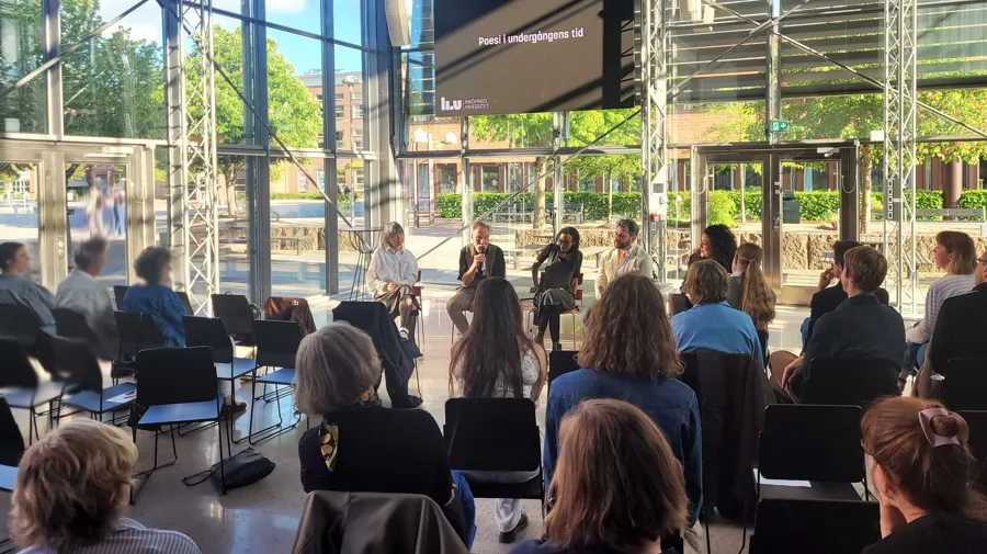 Personer som lyssnar på poesi i en sal.