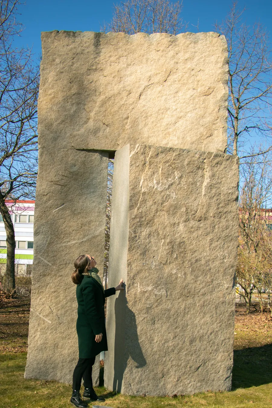 En kvinna står bredvid en stor stenskulptur.