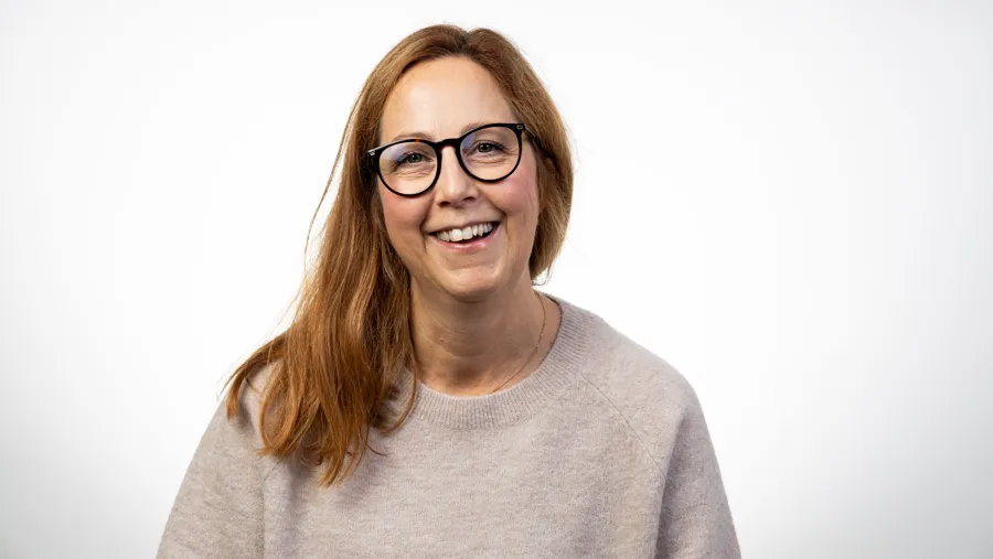 En kvinna med glasögon som ler mot kameran.