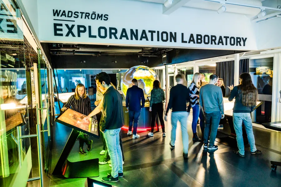 En grupp människor som står i en utstälning. Skylt med texten Wadströms Exploranation Laboratory.
