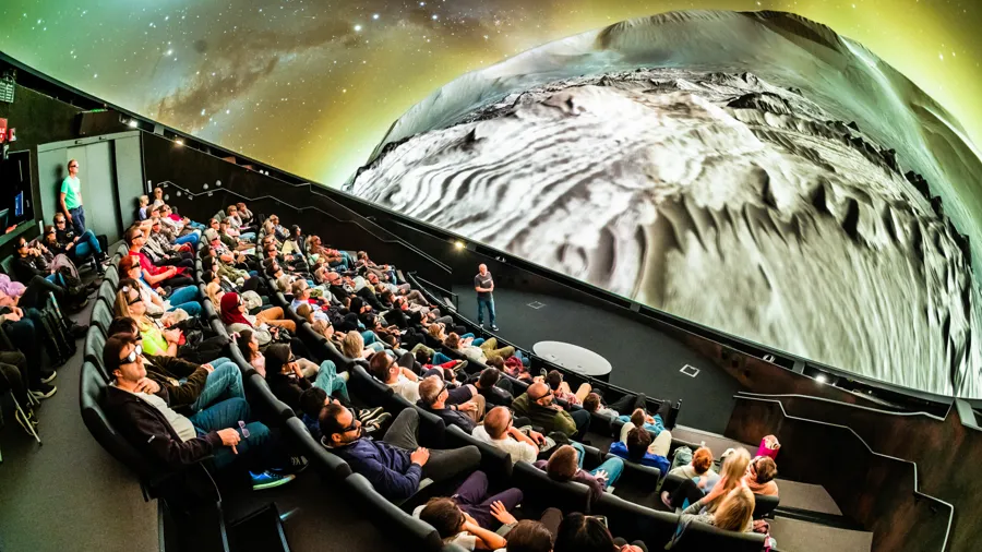 En publik som sitter framför en projektionsduk med en planet.