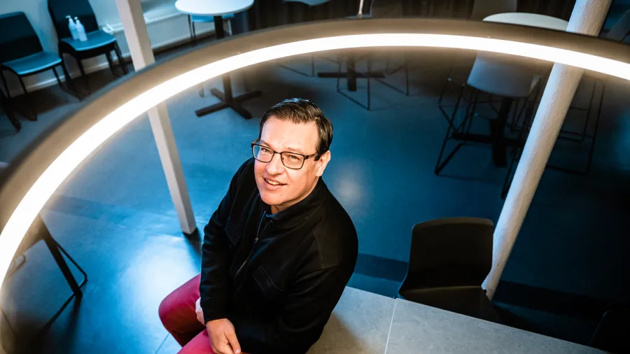 En man sitter på en stol i ett rum.