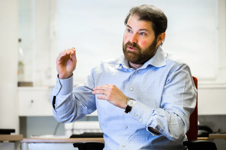 En man som sitter i en stol med händerna i luften.