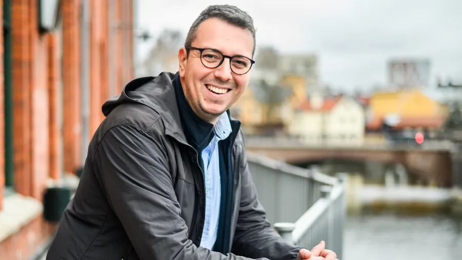 A man leaning on a rail next to a body of water.